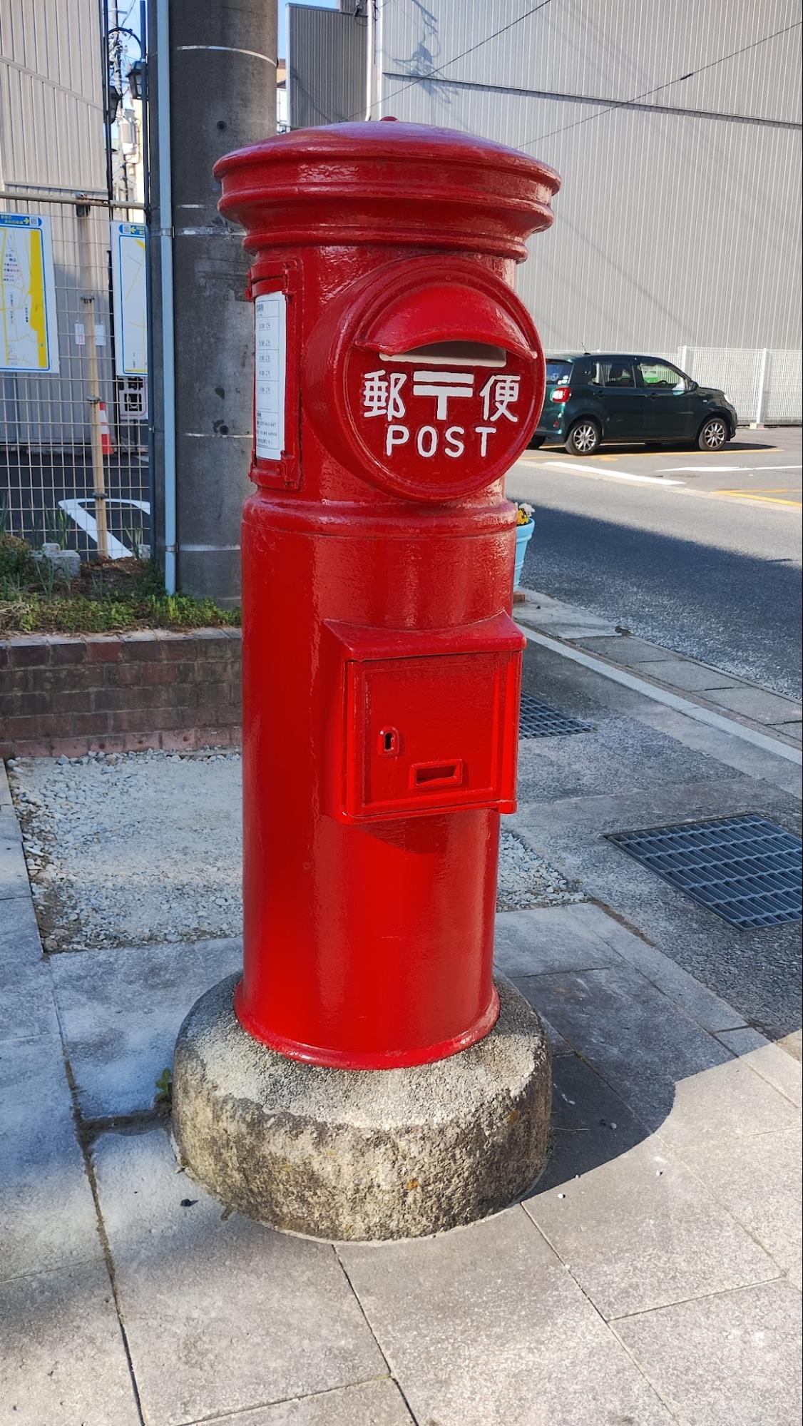 A classic red cylindrical Japanese post box
