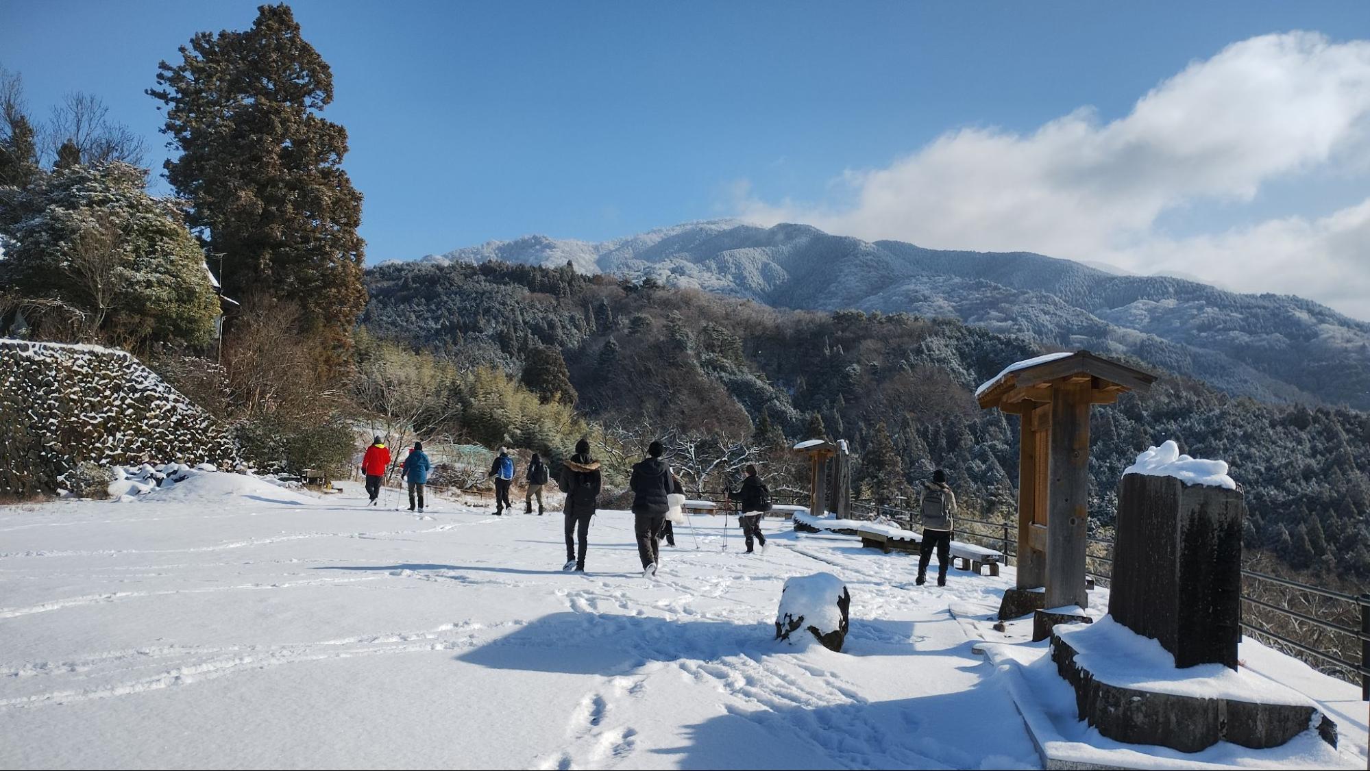 Travelers walking through snow with mountain views
